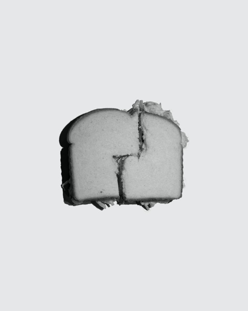 Black and white chicken salad sandwich on solid background